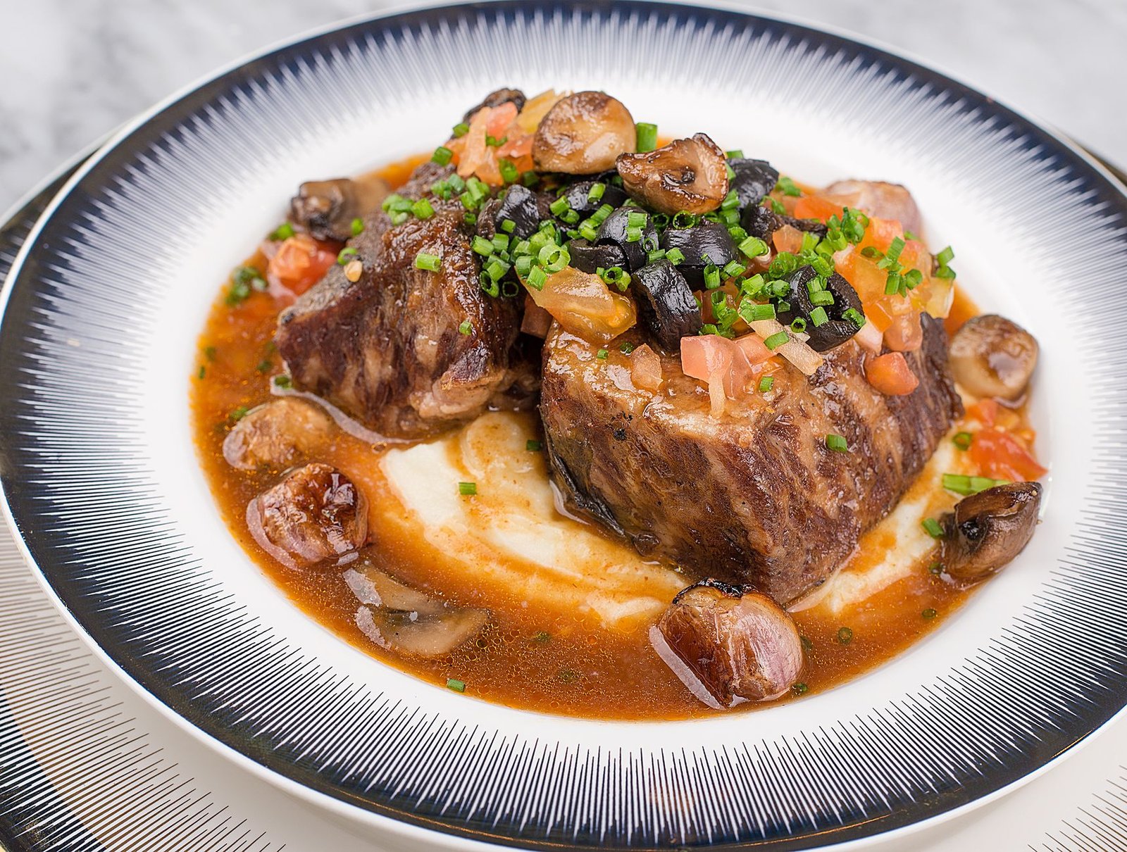 Braised short ribs served over mashed potatoes with mushrooms