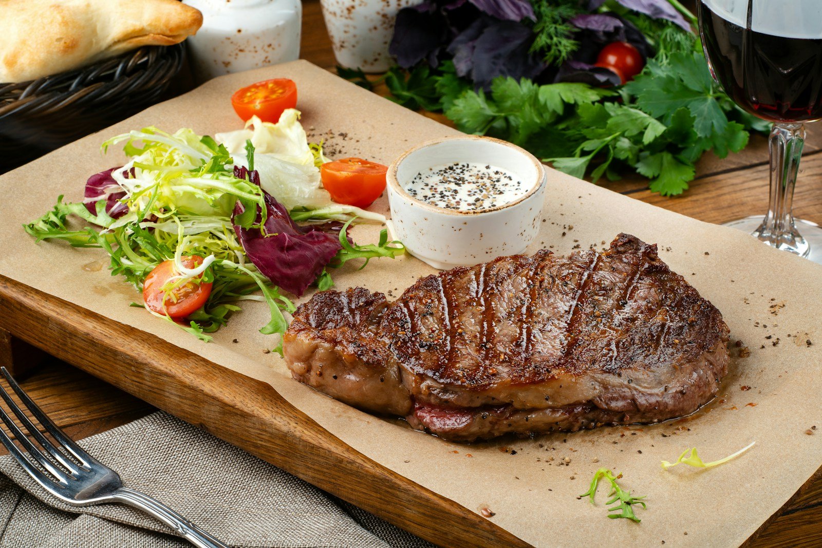 Grilled New York strip steak plated with salad and a glass of red wine
