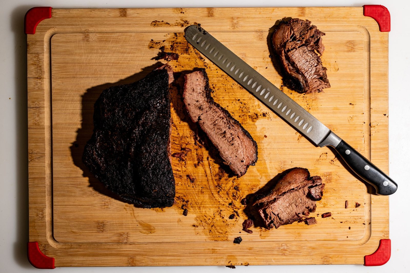 Sliced smoked beef with a dark bark crust on a cutting board