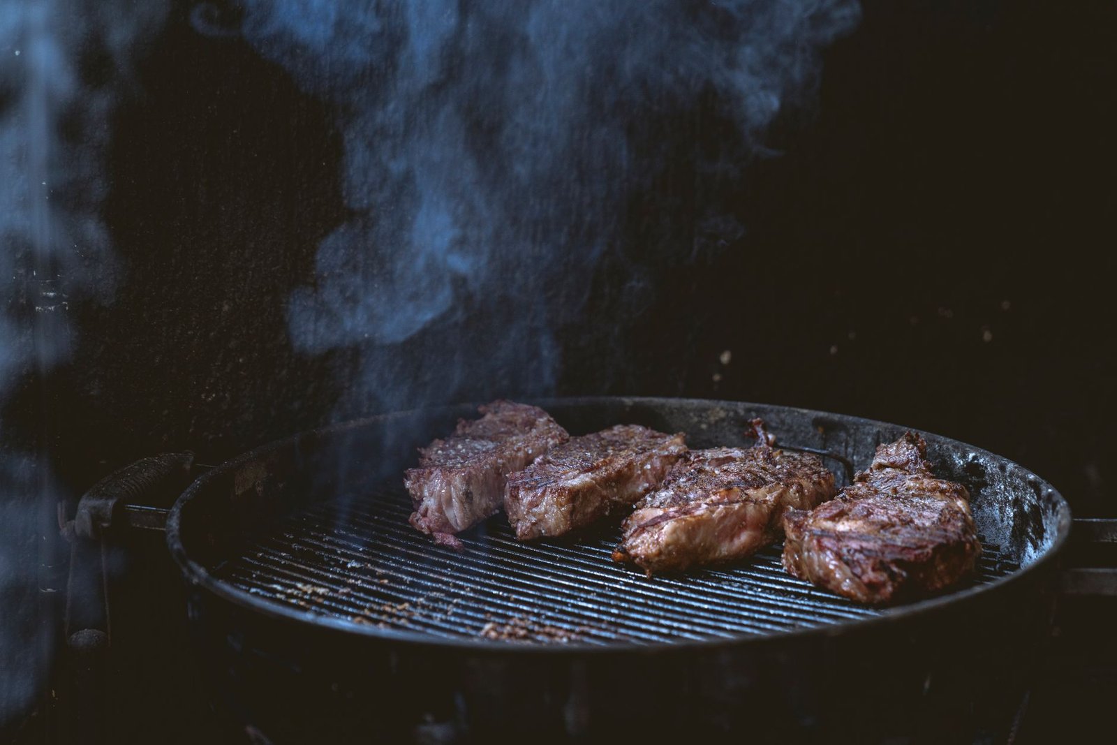 Steaks grilling on a smoky barbecue