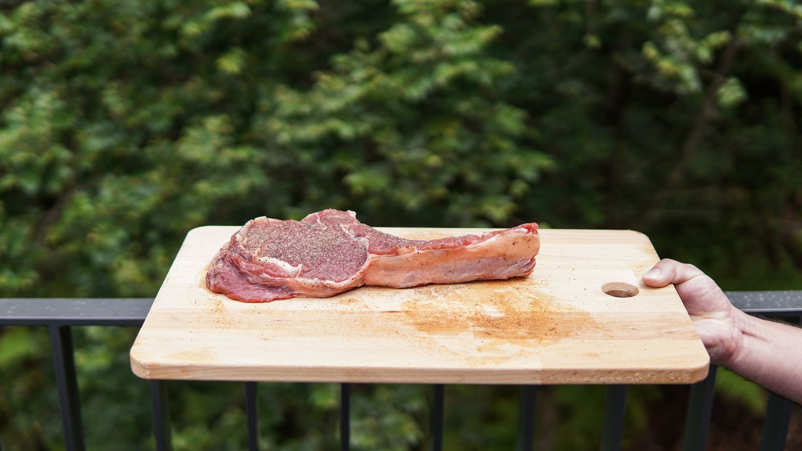 Raw seasoned tomahawk steak with long bone on a wooden board